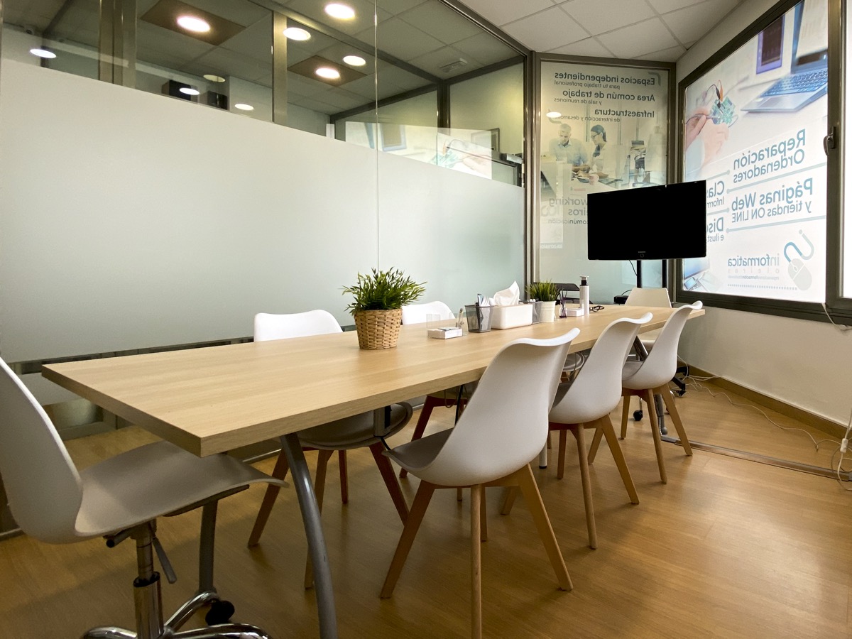 Sala de reuniones con mesa, sillas blancas y pantalla TV en Oleiros